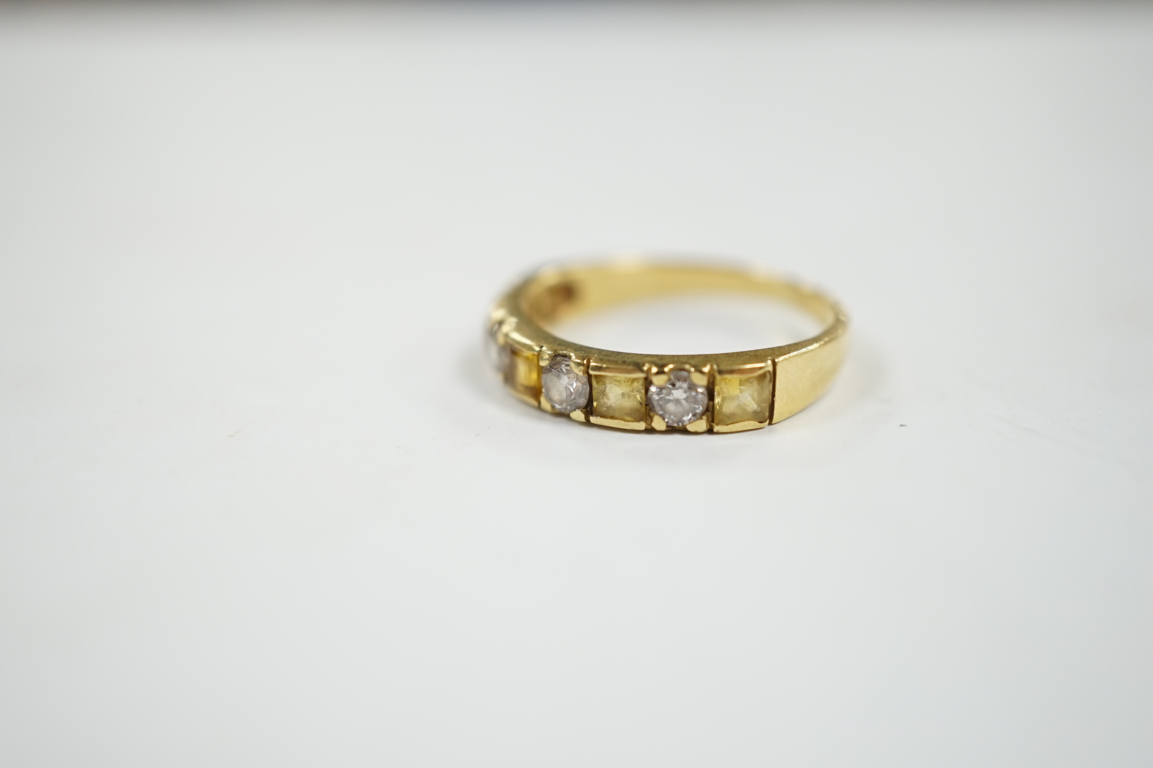 A yellow metal, five stone square cut yellow sapphire and four stone round cut diamond set half hoop ring, size N, gross weight 3.2 grams.